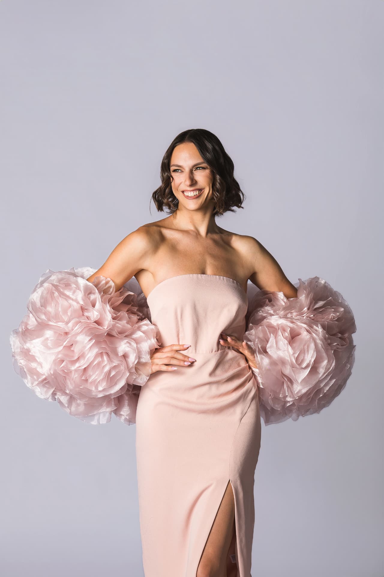 Krista standing confidently in a pink gown with ruffled sleeves